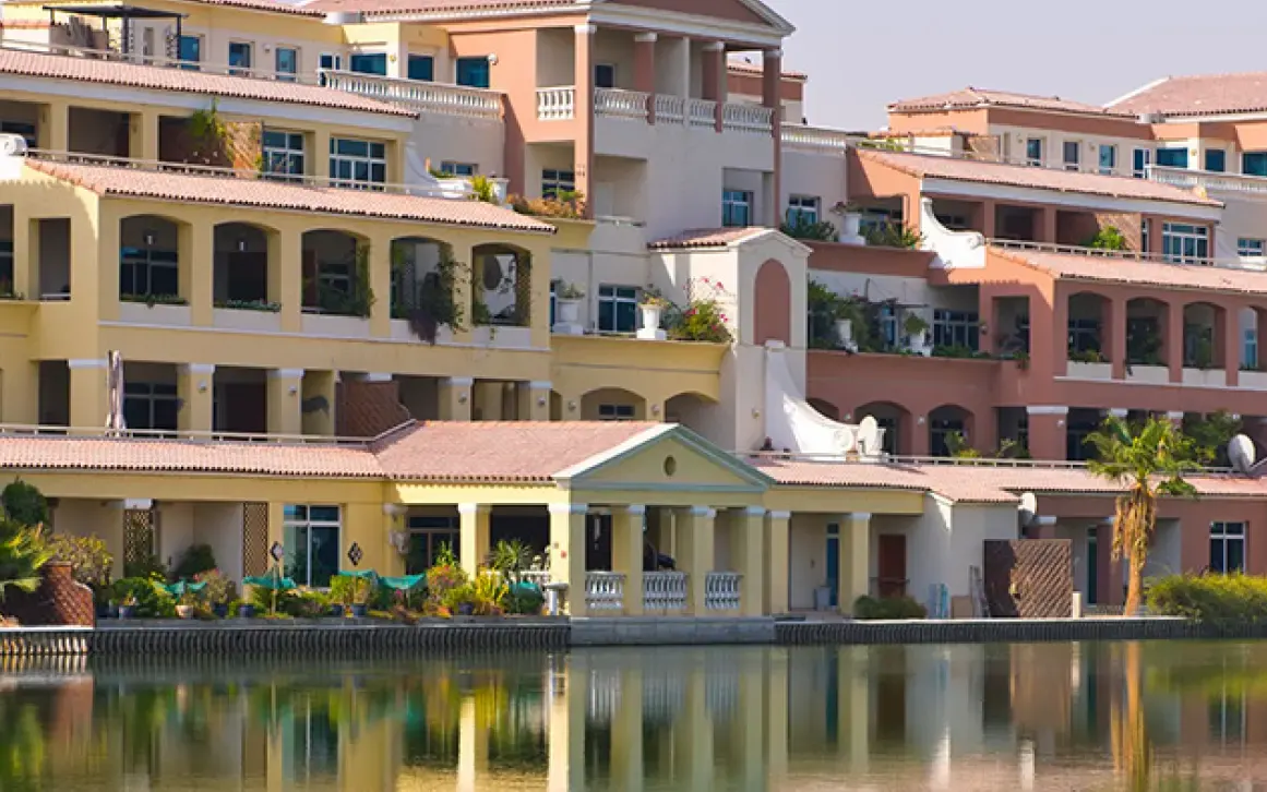 Completed Green Community lakefront buildings in Dubai Investments Park. Area context, not a photograph of Verdana Residence.