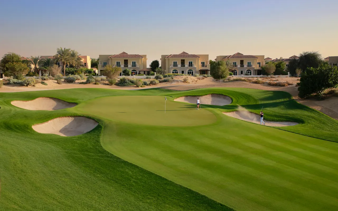 Golf fairway and completed villas beside The Els Club eleventh hole in Dubai Sports City. Area context, not a photograph of Intima villas.