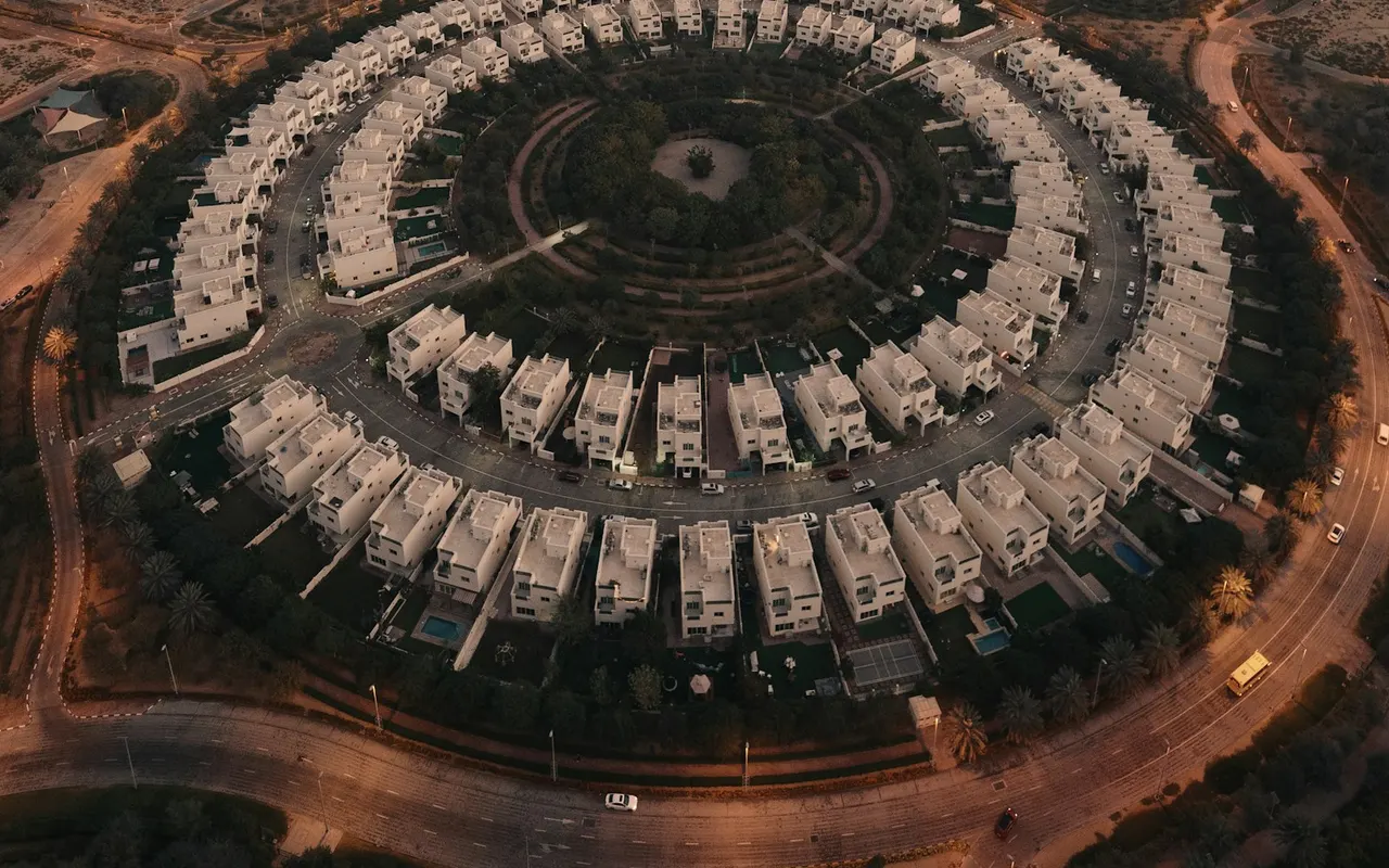 Circular row of completed villas and landscaped courtyard in Jumeirah Village Circle. Area context, not a photograph of Celestara Residences.