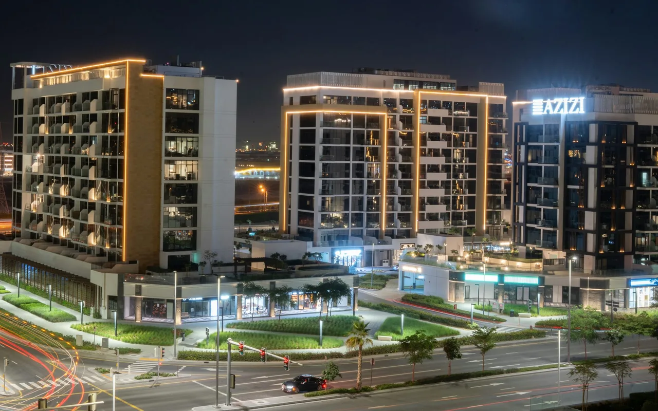 Illuminated apartment buildings and traffic light trails at Azizi Riviera in Meydan One. Area context, not a photograph of La Vue Parc.
