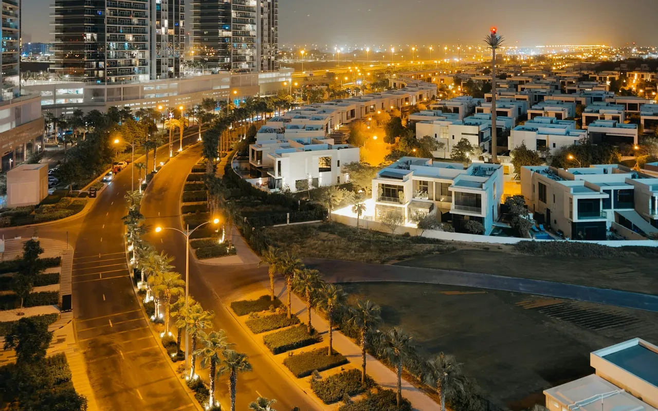 DAMAC Hills apartment towers and villa streets at night. Area context, not a photograph of DAMAC Hills – Golf Veduta.